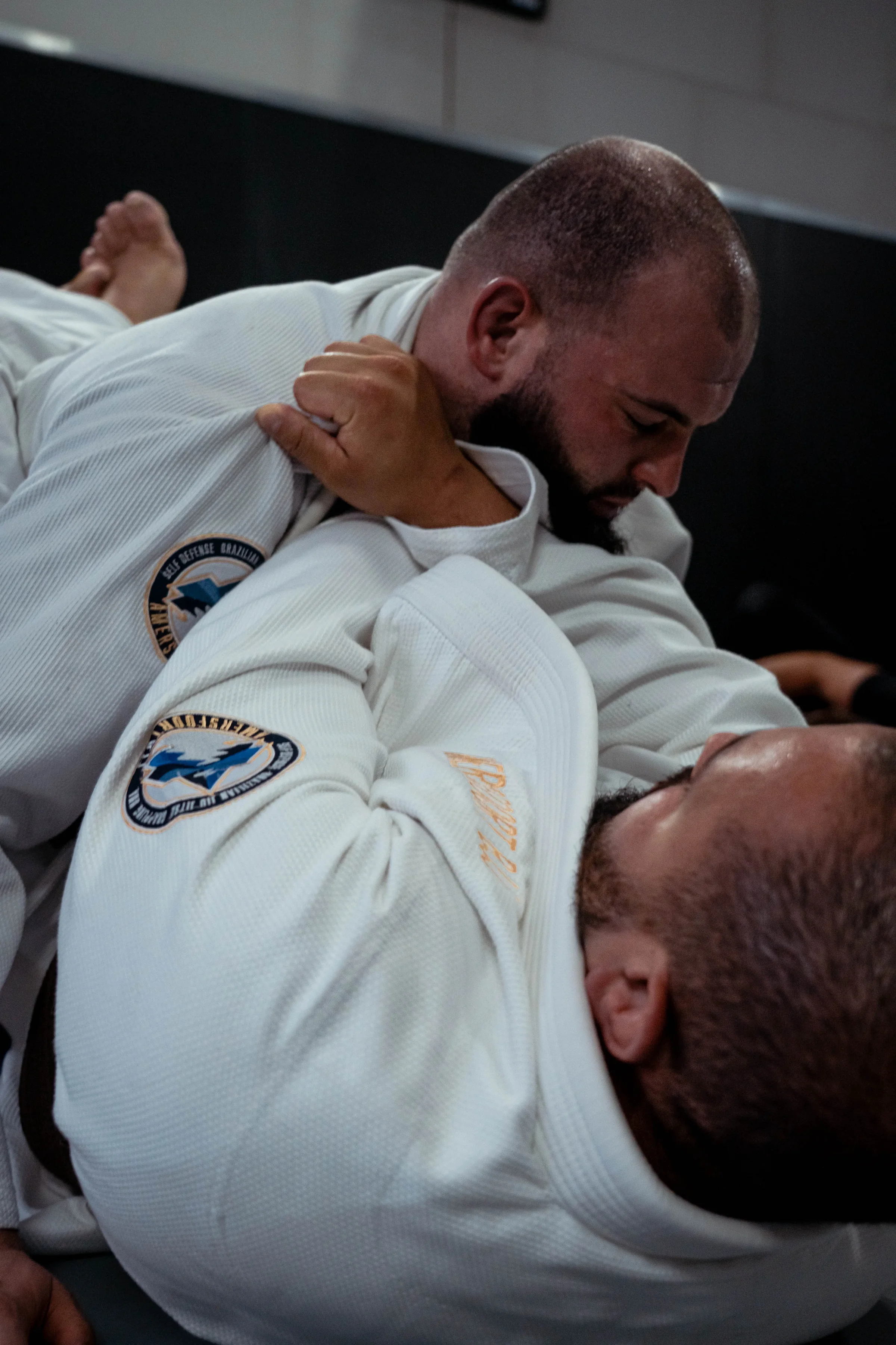 Twee volwassenen in gi vechten om grip tijdens een Brazilian Jiu-Jitsu training in Amersfoort