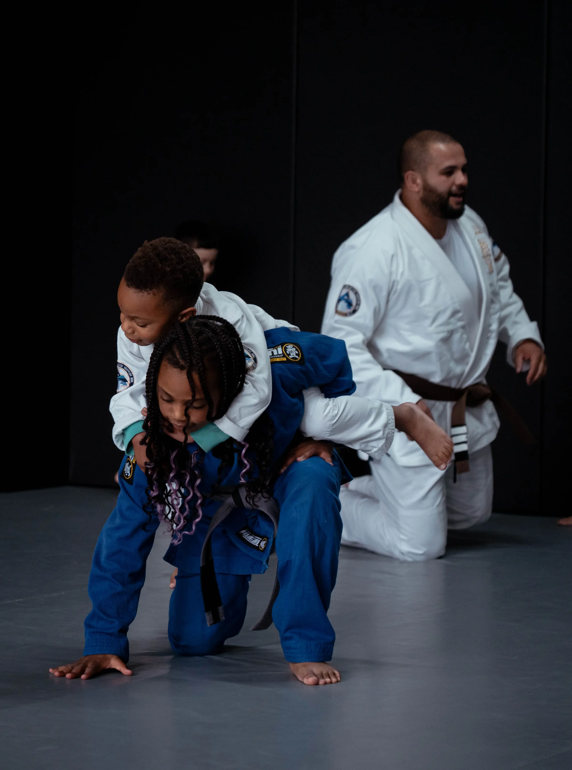 Twee kinderen sparren onder toezicht van de trainer tijdens BJJ Kids