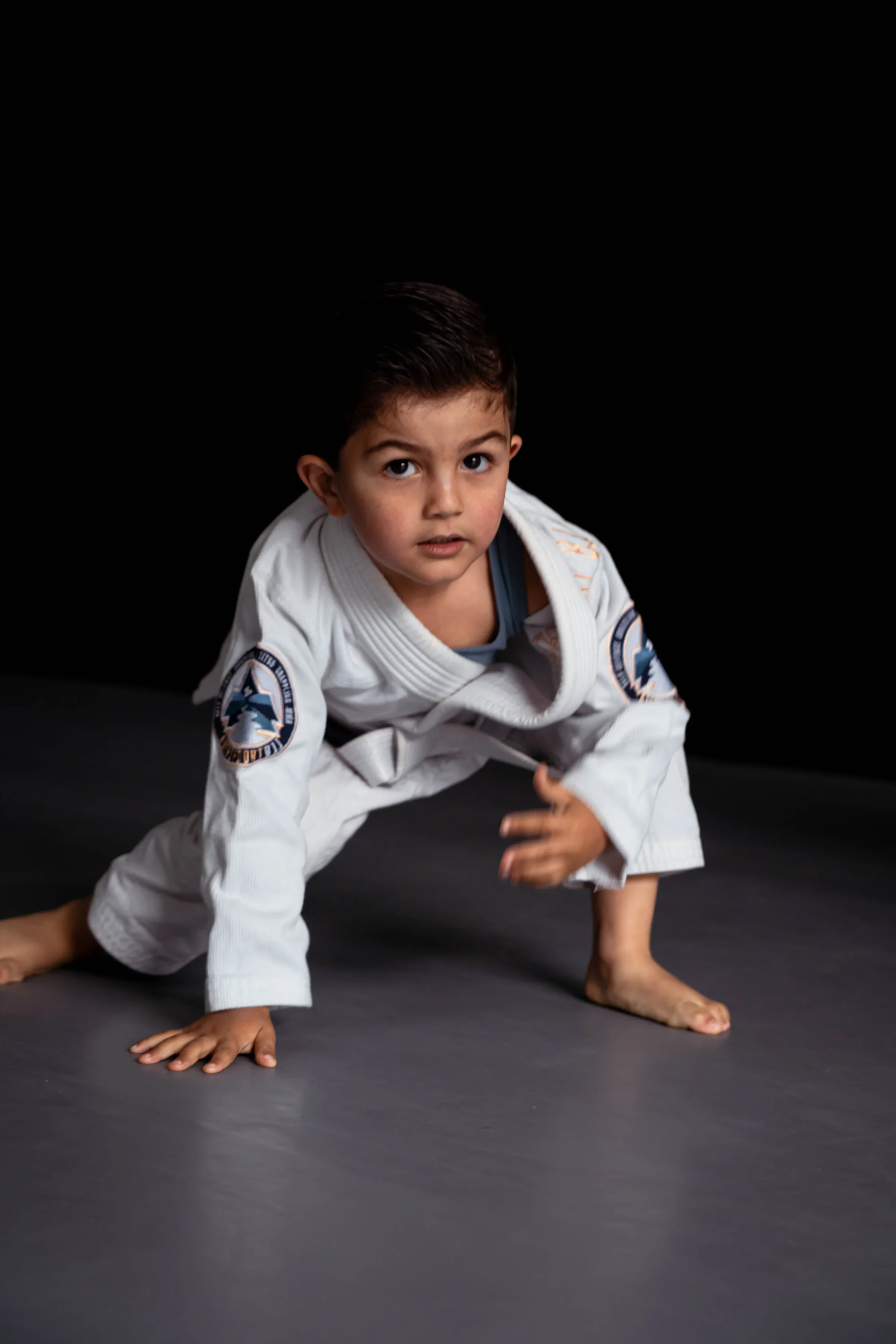 Jong kind in gi op handen en voeten tijdens de Tuimel BJJ les